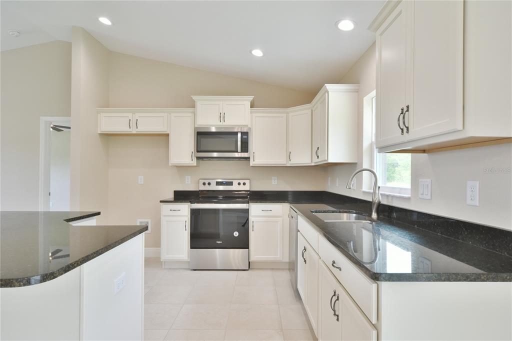 16219 Southwest 48th Circle Ocala, FL 34473 - Photo 22 of 36 a kitchen with stainless steel appliances granite countertop a sink stove and cabinets