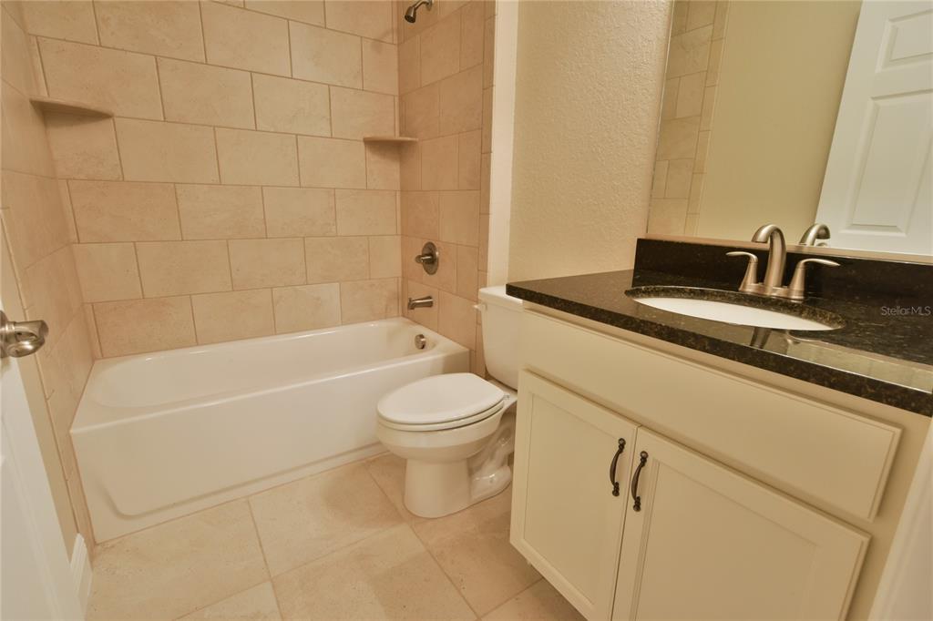 16219 Southwest 48th Circle Ocala, FL 34473 - Photo 34 of 36 a bathroom with a granite countertop toilet a sink and bathtub