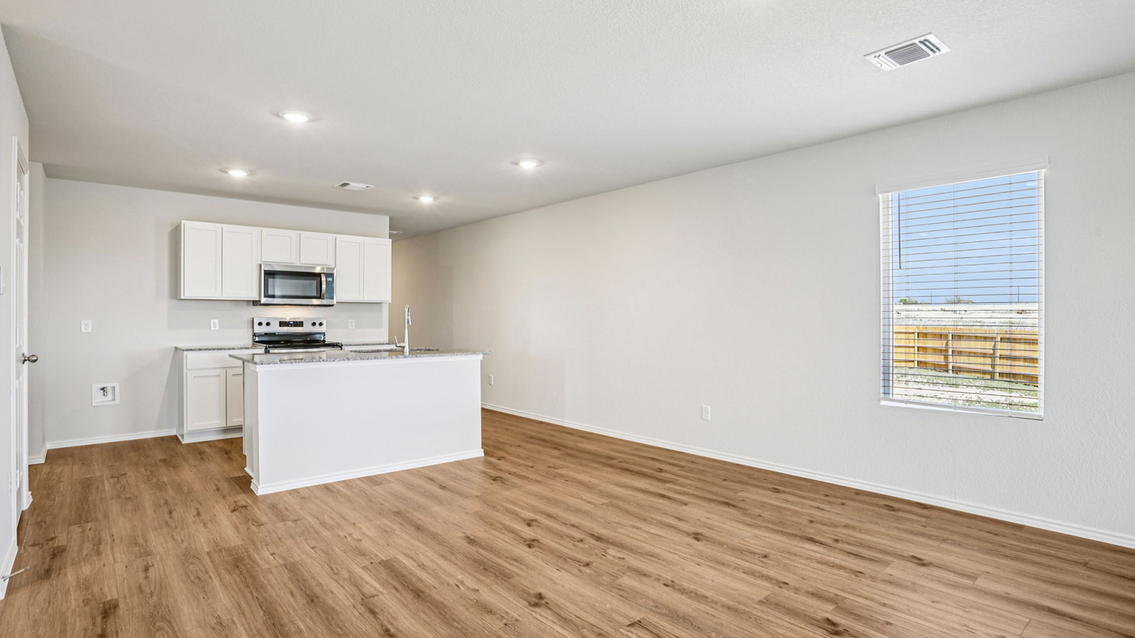 148 Wyatt Way Jarrell, TX 76537 - Photo 8 of 33 Open-concept kitchen and living area featuring wood-finish flooring, white cabinetry, a kitchen island with sink, and recessed lighting