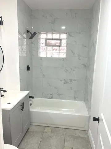 a bathroom with a bathtub a window and a shower