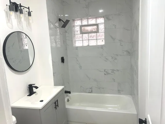 a bathroom with a bath tub a sink and mirror