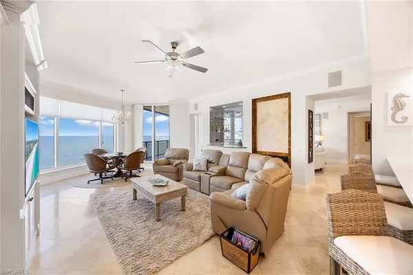 a living room with furniture a chandelier and kitchen view