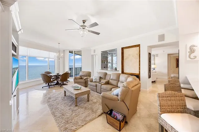 a living room with furniture a chandelier and kitchen view