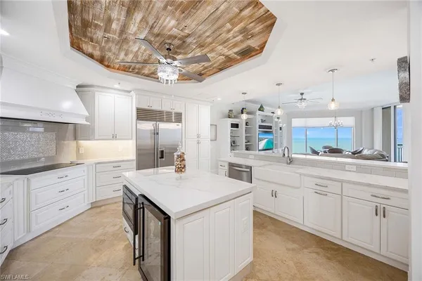 a kitchen with stainless steel appliances kitchen island granite countertop a sink dishwasher stove and white cabinets with wooden floor