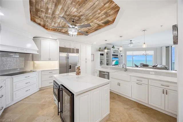 a kitchen with stainless steel appliances kitchen island granite countertop a sink dishwasher stove and white cabinets with wooden floor