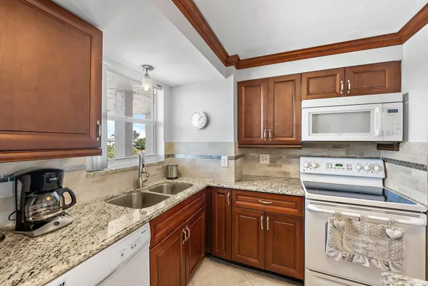a kitchen with granite countertop a sink a stove and cabinets