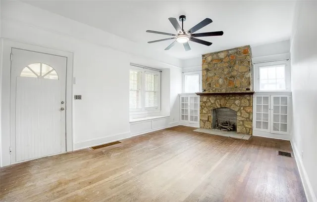 an empty room with windows fireplace and wooden floor