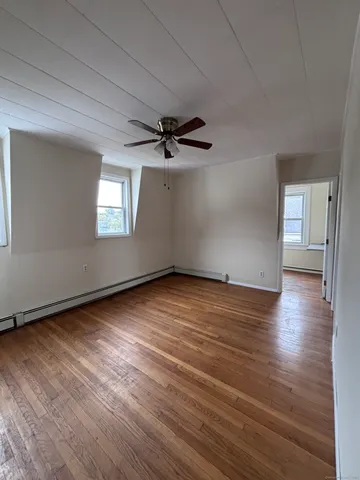 an empty room with wooden floor chandelier fan and windows