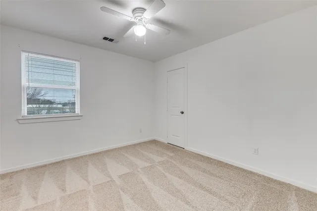 an empty room with a window and a fan
