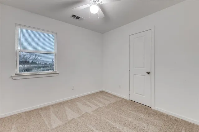 an empty room with a ceiling fan and window