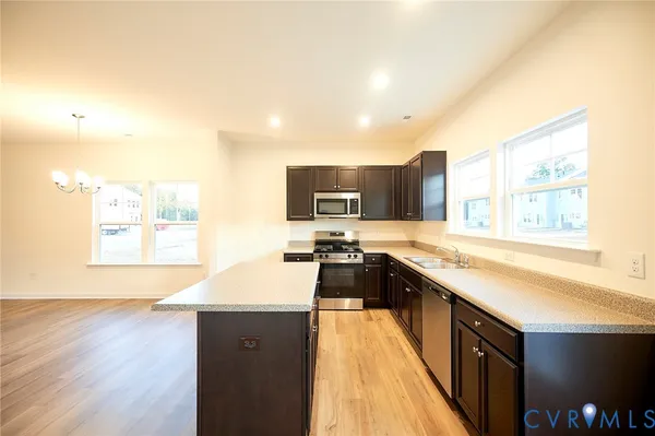 a large kitchen with stainless steel appliances kitchen island granite countertop a sink and wooden cabinets