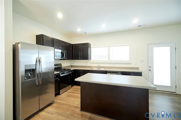 a kitchen with stainless steel appliances granite countertop a refrigerator a sink a stove and island