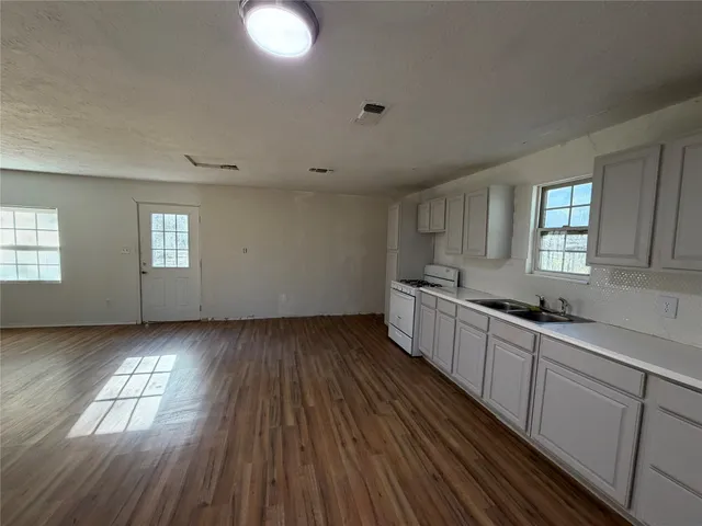 a kitchen with wooden floors and white walls