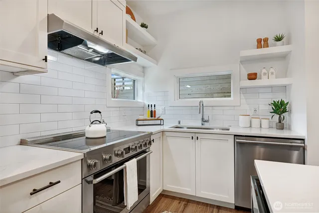 a kitchen with stainless steel appliances a sink a stove and cabinets