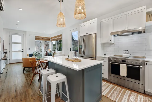 a kitchen with stainless steel appliances a stove a sink dishwasher a stove and a refrigerator with wooden floor