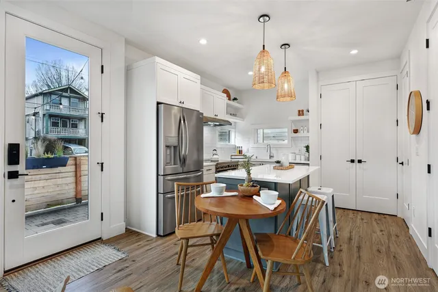 a kitchen with stainless steel appliances kitchen island granite countertop a refrigerator a stove a microwave oven a dining table and chairs with wooden floor