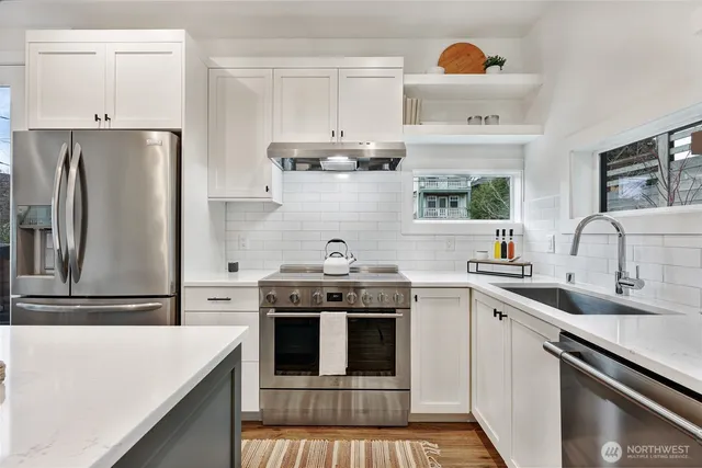 a kitchen with stainless steel appliances a stove a sink and a refrigerator