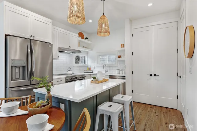 a kitchen with stainless steel appliances a stove a refrigerator and a dining table