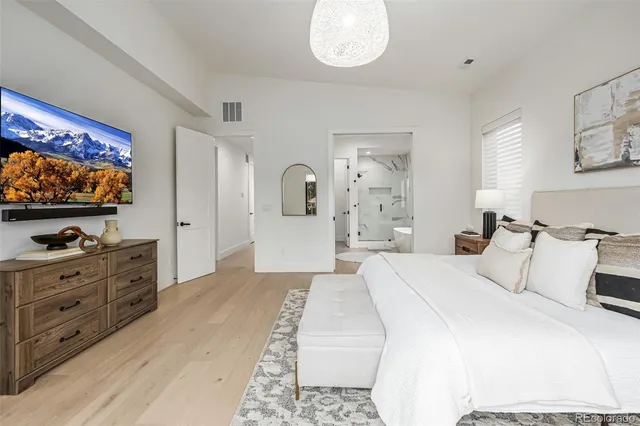 a spacious bedroom with a bed and a flat screen tv