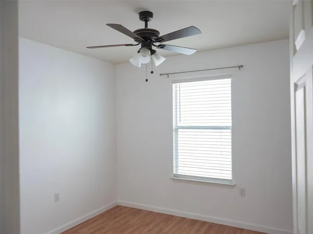 an empty room with a window and a fan