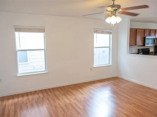 a view of an empty room with window and wooden floor