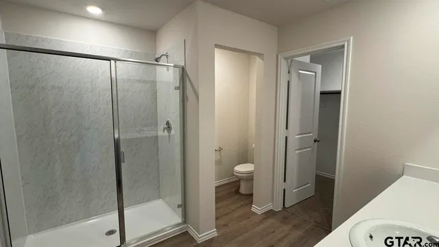 a bathroom with a granite countertop mirror a toilet and a shower