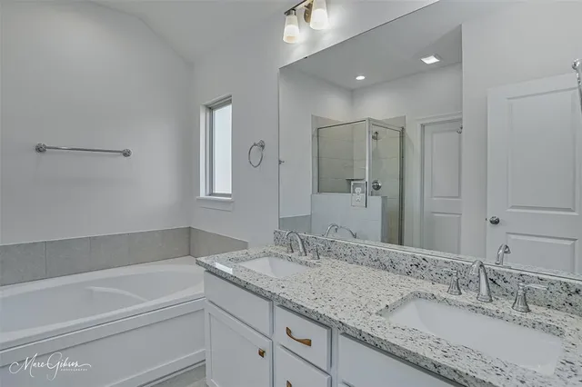 a bathroom with a granite countertop double vanity sink and mirror with bathtub