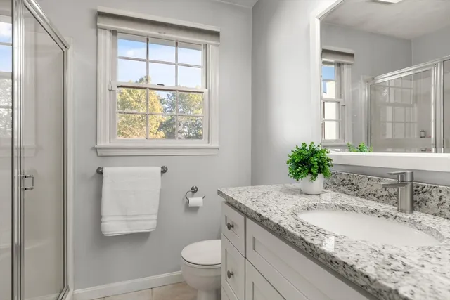 a bathroom with a granite countertop sink mirror vanity and toilet