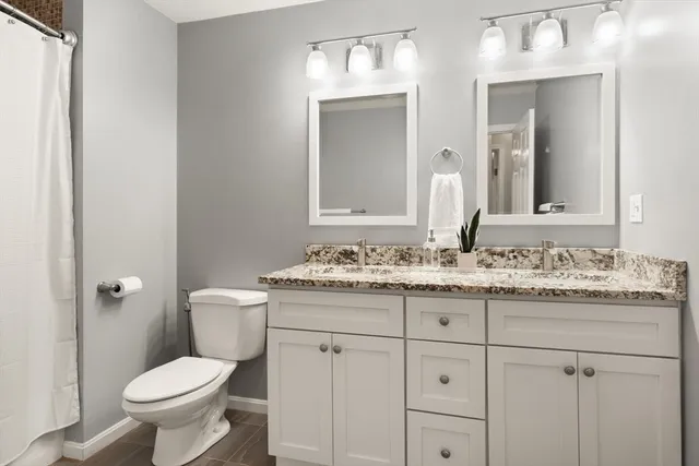 a bathroom with a granite countertop toilet sink and mirror