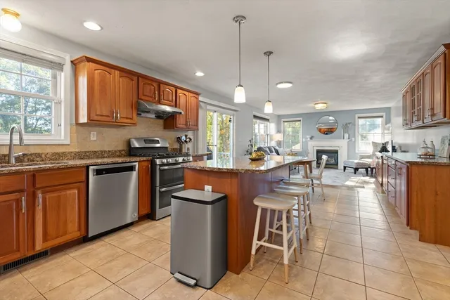 a kitchen with stainless steel appliances granite countertop a stove top oven a sink a dining table and chairs