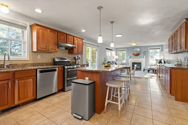 a kitchen with stainless steel appliances granite countertop a stove top oven a sink a dining table and chairs