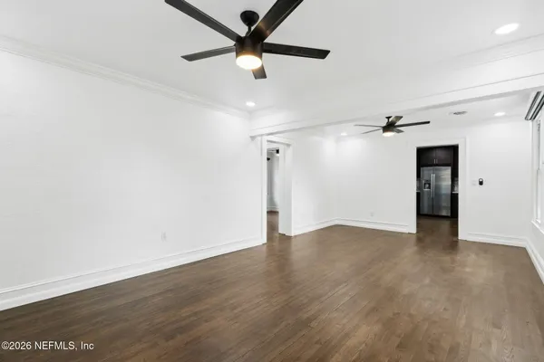 an empty room with wooden floor ceiling fan and windows