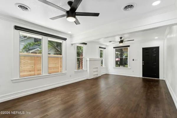 a view of an empty room with wooden floor and a window