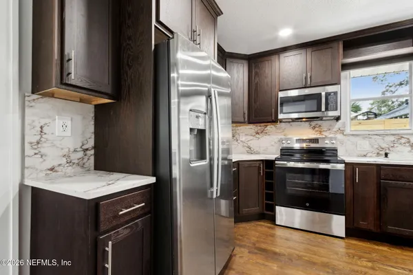 a kitchen with stainless steel appliances granite countertop a stove refrigerator and microwave