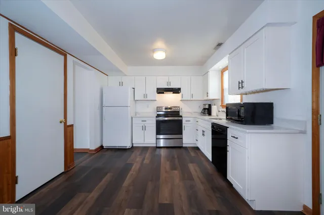 a kitchen with white cabinets stainless steel appliances and wooden floor