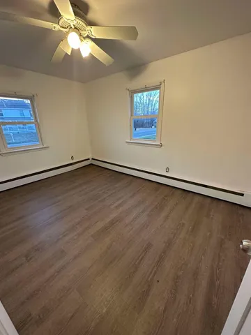 an empty room with wooden floor fan and windows