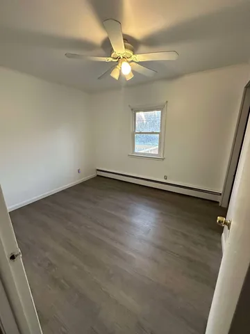 an empty room with wooden floor and fan