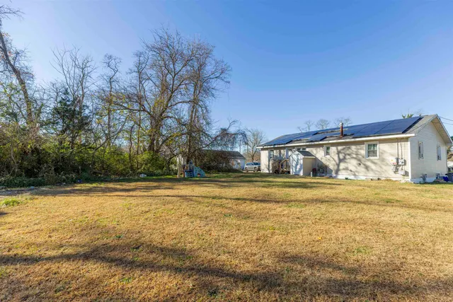 a big white house with a big yard and large trees