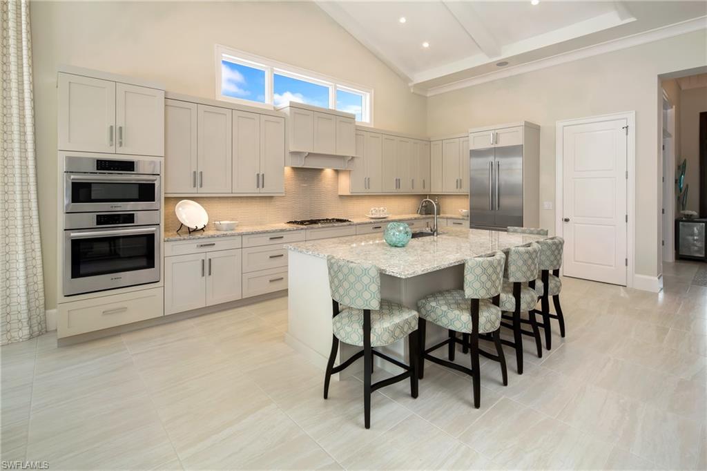 6818 Mangrove Avenue Naples, FL 34109 - Photo 10 of 24 a kitchen with stainless steel appliances kitchen island granite countertop a table chairs sink and cabinets