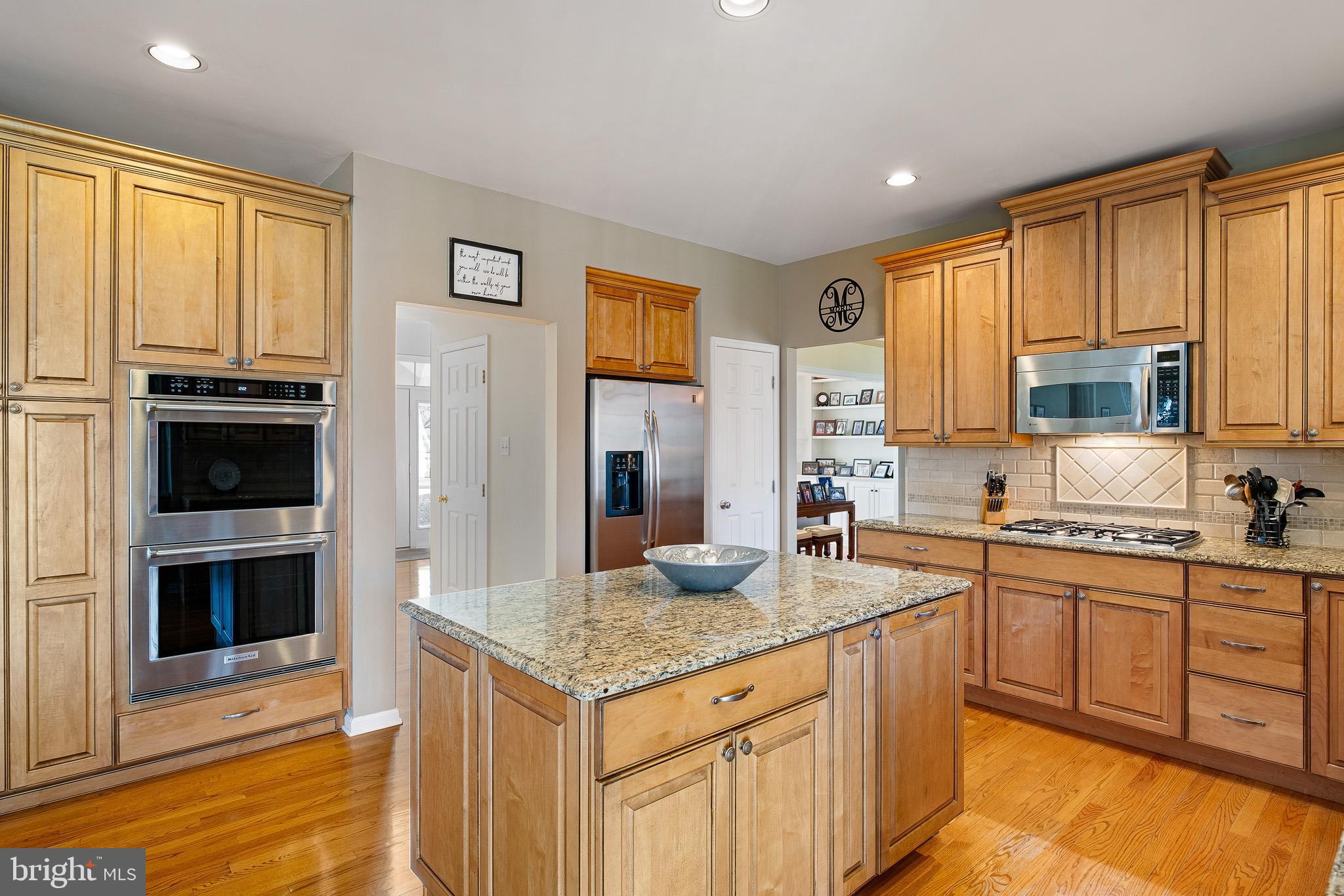 26 Woodside Farm Road Garnet Valley, PA 19060 - Photo 35 of 57 a kitchen with stainless steel appliances granite countertop a stove top oven a sink dishwasher and a refrigerator with wooden floor