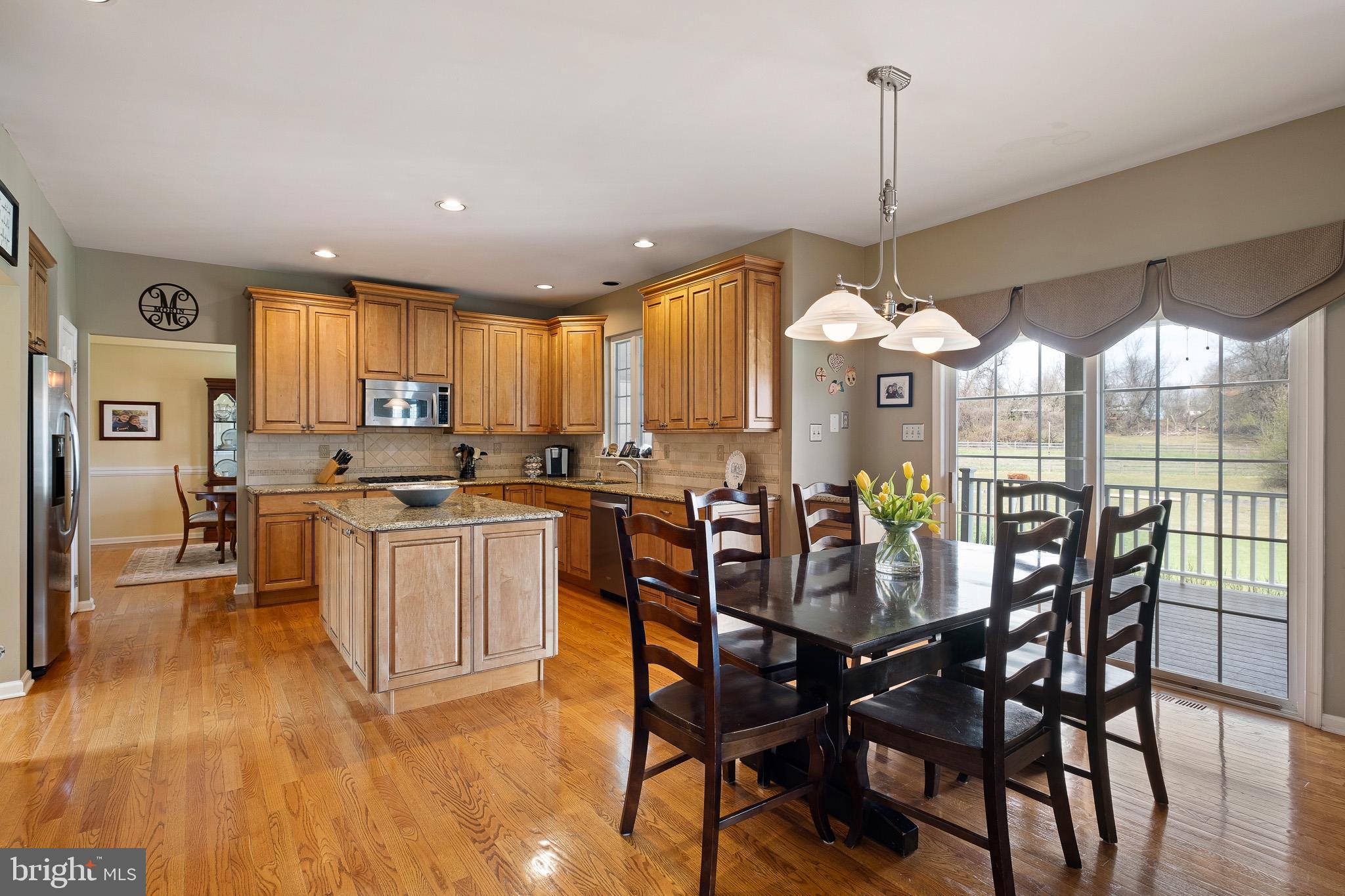 26 Woodside Farm Road Garnet Valley, PA 19060 - Photo 40 of 57 a kitchen with stainless steel appliances granite countertop wooden floor dining table and chairs