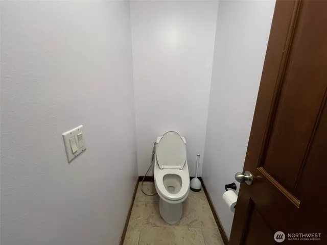 wooden floor with exposed radiator and toilet