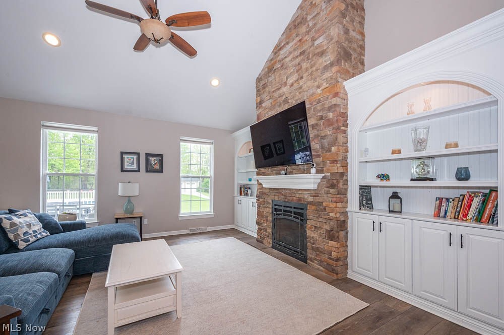 6787 South Palmyra Road Canfield, OH 44406 - Photo 11 of 30 Vaulted living area featuring a floor-to-ceiling stacked stone fireplace with a white mantel, built-in cabinetry, wood-finish flooring, and recessed lighting