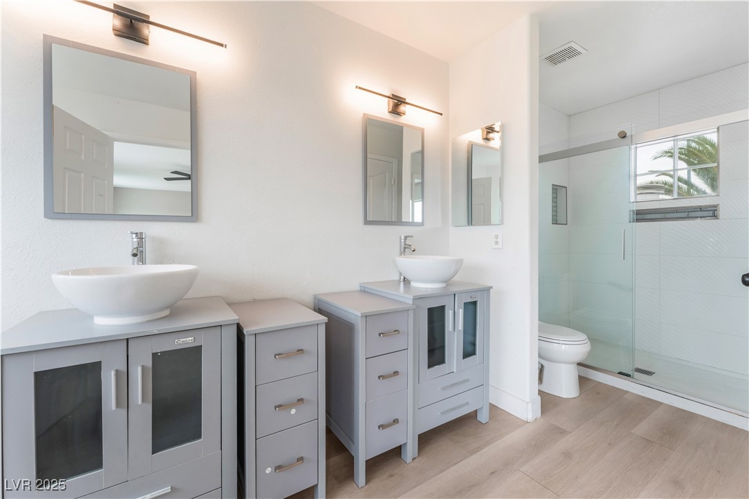3695 Funston Way Las Vegas, NV 89129 - Photo 4 of 43 Bathroom with a shower stall, two vanities, and light wood-style flooring