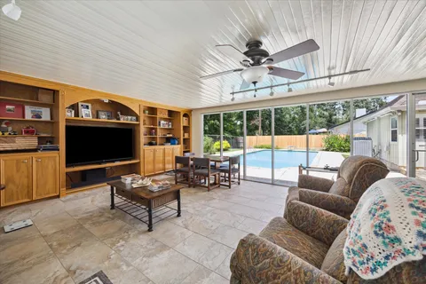 a living room with furniture a ceiling fan and a flat screen tv