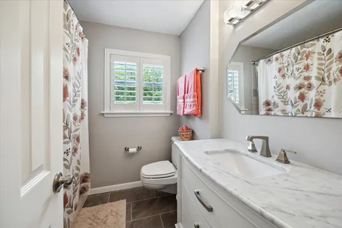 a bathroom with a granite countertop bathtub sink vanity mirror and toilet