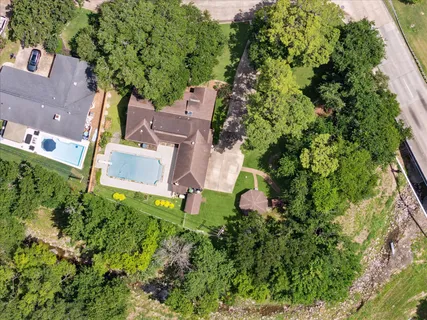 an aerial view of residential house with outdoor space and trees all around