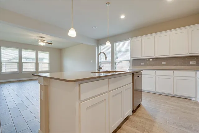a kitchen with white cabinets and window