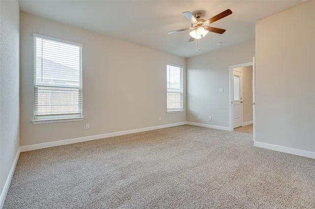 an empty room with windows and ceiling fan