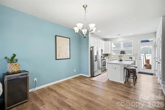 a kitchen with stainless steel appliances granite countertop a refrigerator a sink dishwasher a dining table and chairs with wooden floor